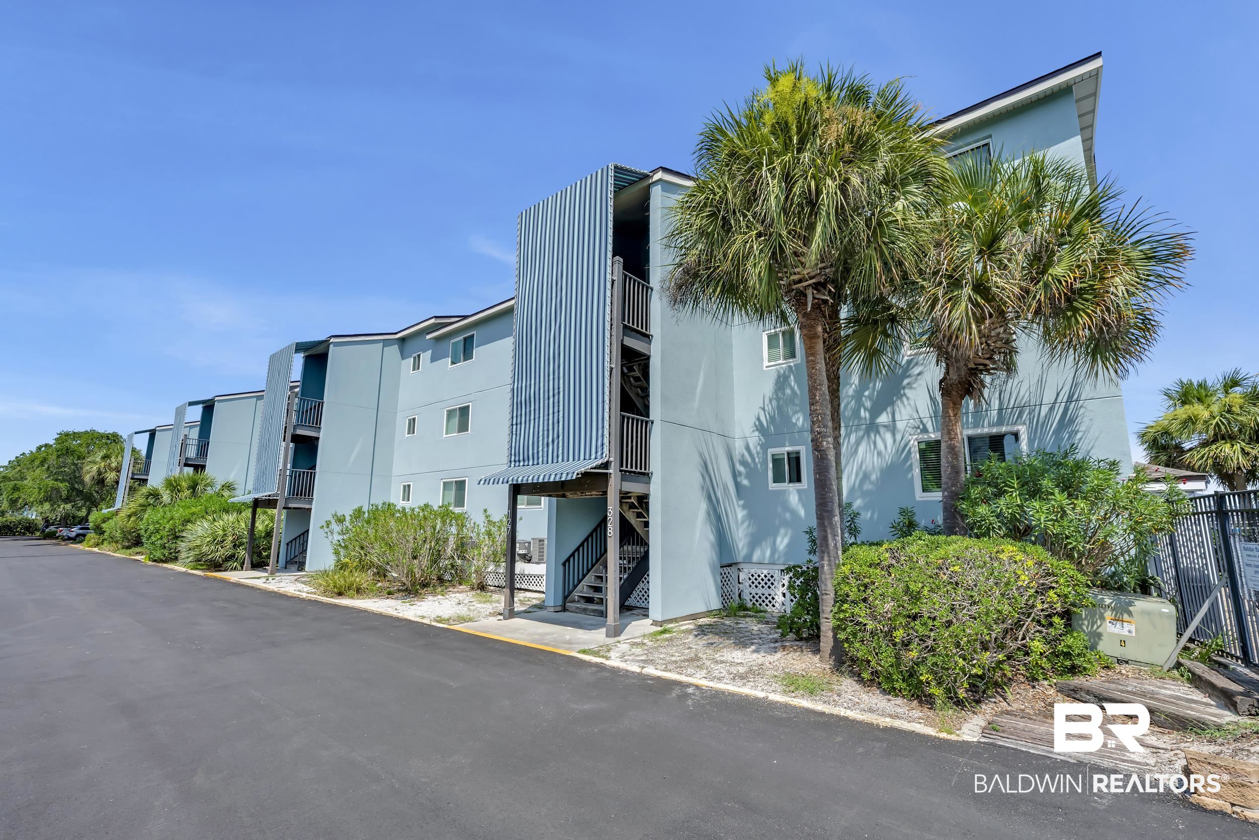 14100 River Road, Unit 211 Pensacola, FL 32507 - Photo 43 of 56 Multi-story residential building with light blue siding, white window frames, and exterior stairwells
