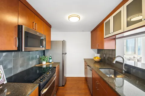 a kitchen with granite countertop a sink a stove and cabinets