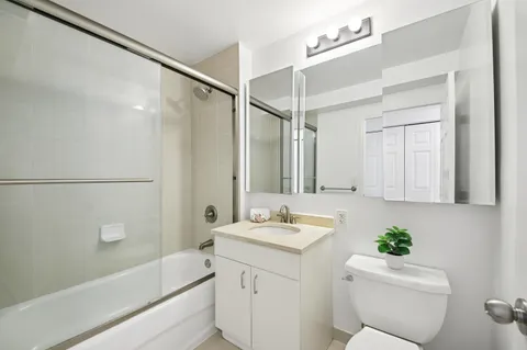 a bathroom with a granite countertop sink a toilet a mirror and shower