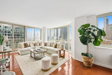 a living room with furniture floor to ceiling window and wooden floor