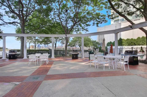a view of a patio with a dining table and chairs under an umbrella with large trees