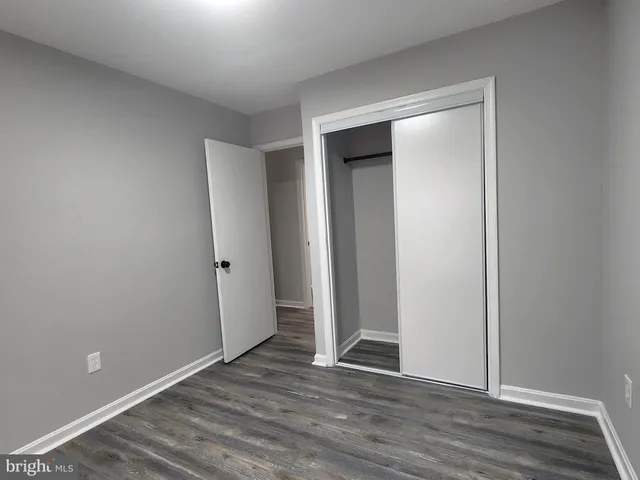 a view of an empty room with wooden floor and closet