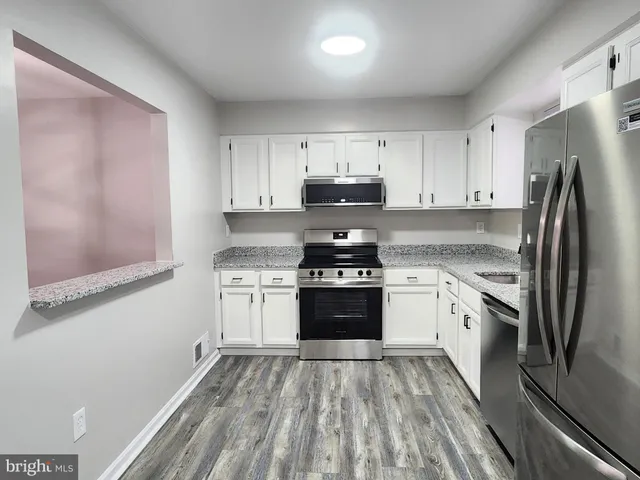 a kitchen with granite countertop a refrigerator stove and sink