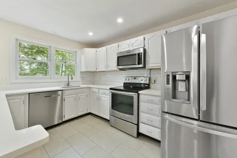 a kitchen with white cabinets stainless steel appliances and window