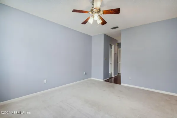 an empty room with closet and a chandelier fan