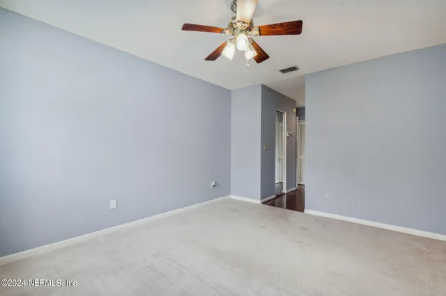 an empty room with closet and a chandelier fan