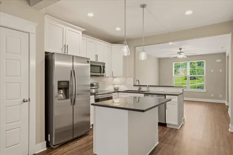 a kitchen with stainless steel appliances granite countertop a refrigerator a sink a stove and a wooden floors