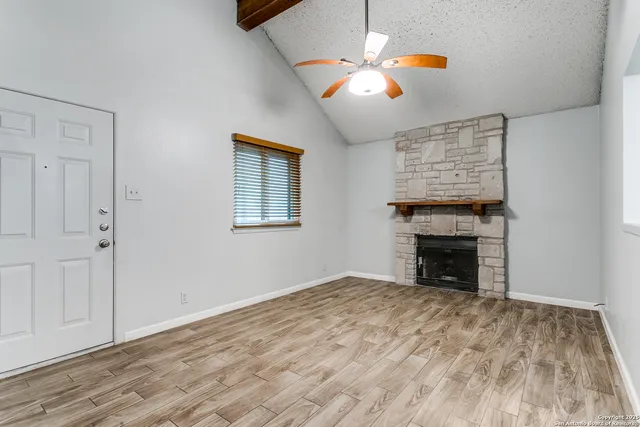 an empty room with windows fireplace and a ceiling fan