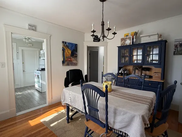 a view of a dining room with furniture a chandelier and wooden floor