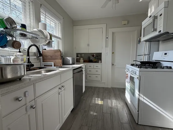 a kitchen with stainless steel appliances a sink dishwasher a stove top oven a refrigerator with wooden floor