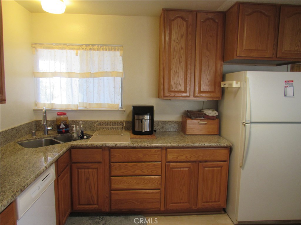 26541 Chambers Avenue Menifee, CA 92586 - Photo 35 of 61 a kitchen with granite countertop wooden cabinets and white appliances
