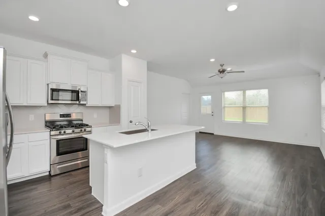 a kitchen with stainless steel appliances granite countertop a stove a sink and a microwave