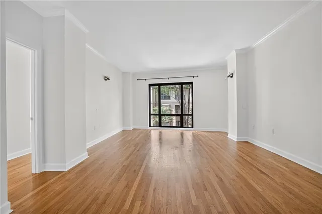 a view of an empty room with wooden floor and fan