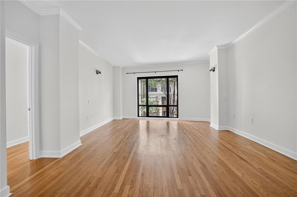 a view of an empty room with wooden floor and fan