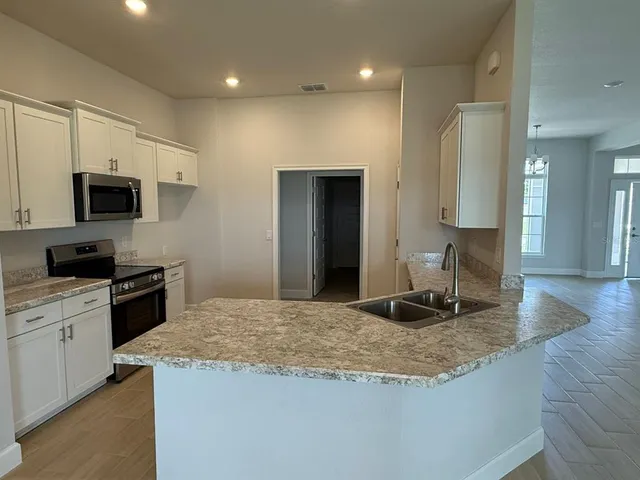 a kitchen with kitchen island granite countertop a sink appliances and cabinets