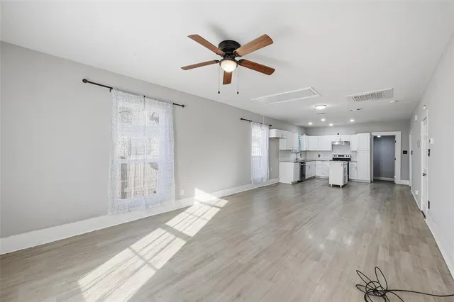 a view of empty room with wooden floor and ceiling fan