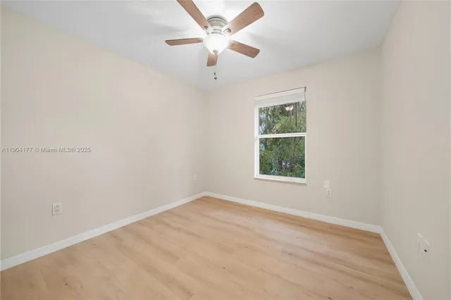 an empty room with a window and a ceiling fan