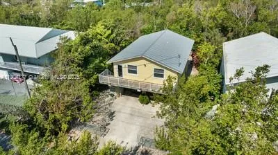 an aerial view of a house with yard and trees in the background