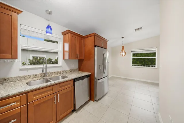 a kitchen with stainless steel appliances granite countertop a sink and a refrigerator