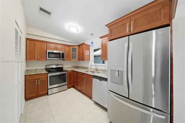 a kitchen with stainless steel appliances granite countertop a refrigerator sink and stove