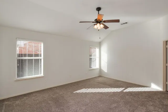 an empty room with wooden floor fan and windows