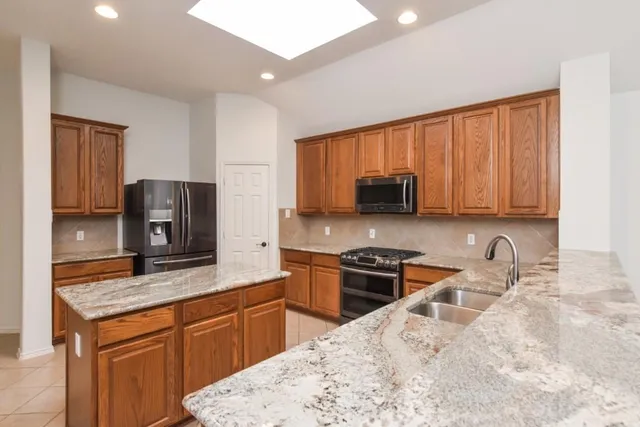 a kitchen with stainless steel appliances granite countertop a sink stove microwave and refrigerator