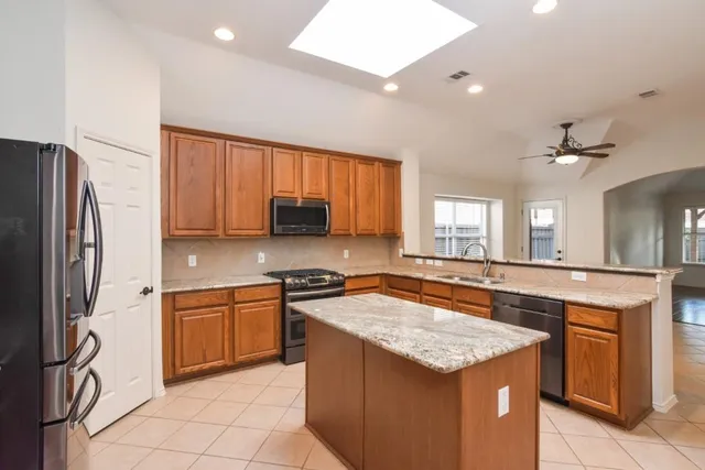 a kitchen with granite countertop a sink stove and refrigerator
