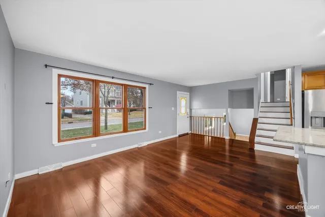 a view of an empty room with window and wooden floor