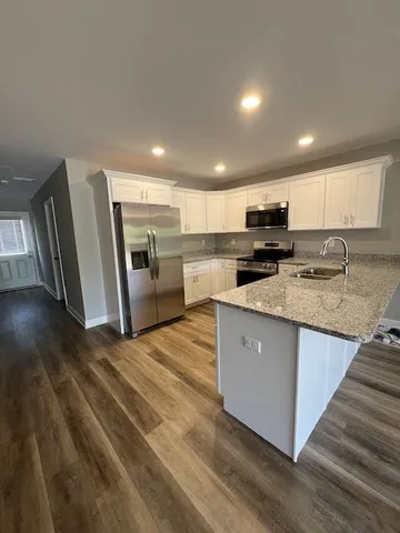 a large kitchen with stainless steel appliances granite countertop a stove a sink dishwasher a microwave oven and a refrigerator with wooden floor