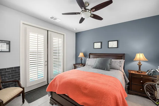 a spacious bedroom with a bed a dresser next to a window