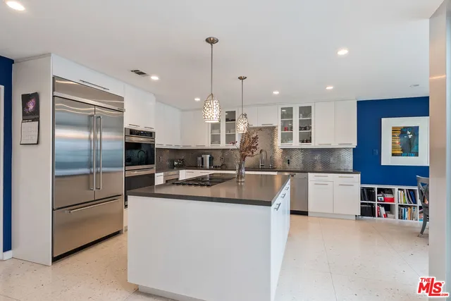 a kitchen with stainless steel appliances granite countertop a refrigerator a stove and a sink