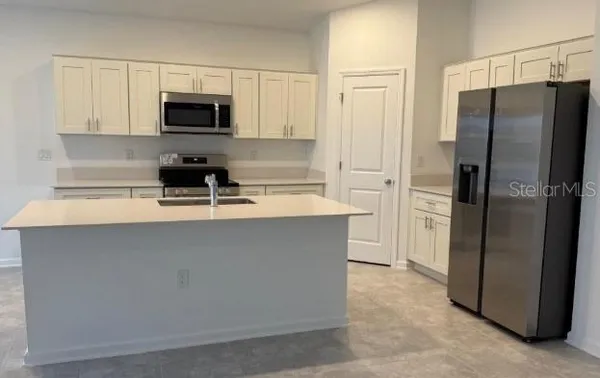 a kitchen with stainless steel appliances a refrigerator a stove a microwave and a sink