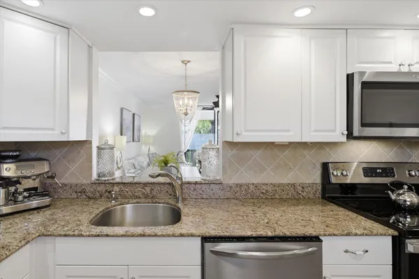 a kitchen with granite countertop a sink a stove and cabinets