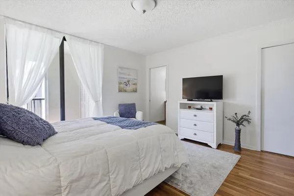 a bedroom with a bed and a flat tv screen on dresser