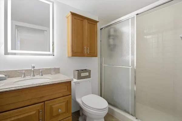 a bathroom with a granite countertop sink toilet and shower