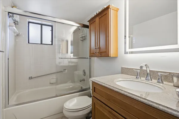 a bathroom with a granite countertop sink toilet and shower