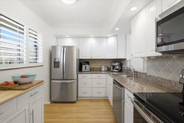 a kitchen with stainless steel appliances granite countertop a refrigerator sink and stove