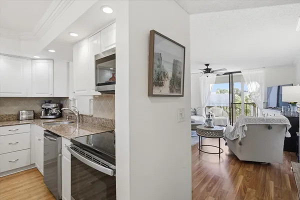 a kitchen with a sink dishwasher a stove and white cabinets with wooden floor