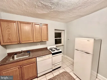a kitchen with granite countertop a refrigerator a sink and white cabinets