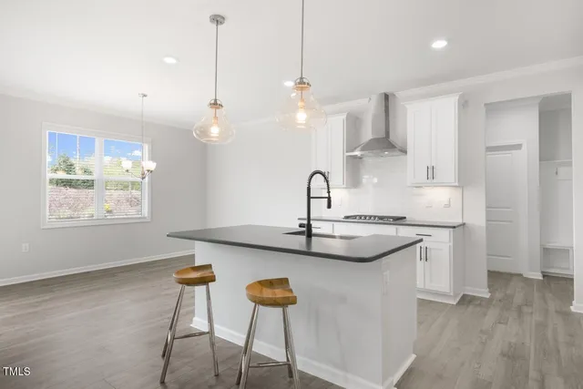 a kitchen with stainless steel appliances granite countertop a sink a stove a refrigerator and island with wooden floor