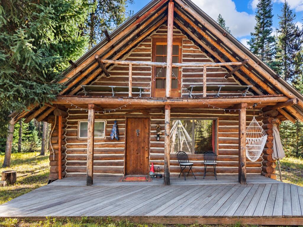507 Secesh River Road McCall, ID 83638 - Photo 8 of 34 Front of the 1980 log cabin, with a full-width covered porch, hammock chair, and gable balcony.