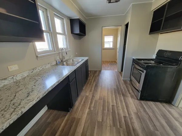 a kitchen with granite countertop a sink stove and cabinets