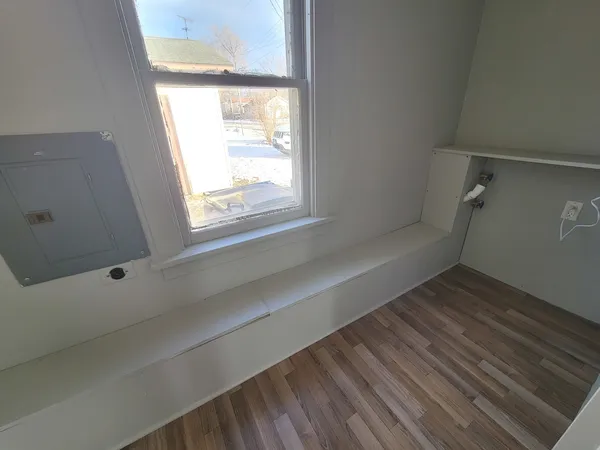 a view of an empty room with wooden floor and a window