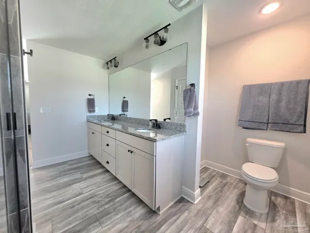 a spacious bathroom with a granite countertop sink a toilet and a mirror