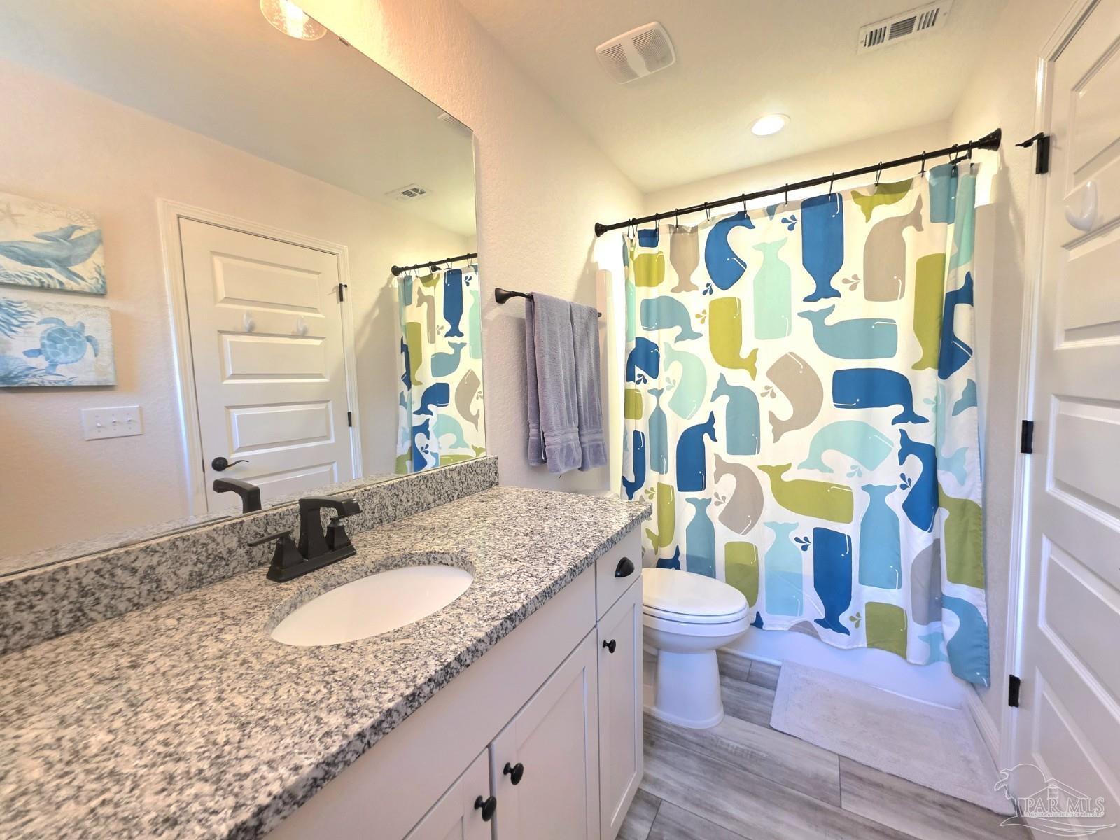 1307 Heron Inlet Pensacola, FL 32506 - Photo 23 of 35 a bathroom with a granite countertop sink a toilet a mirror a shower curtain