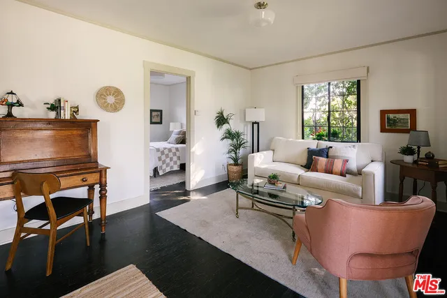 a living room with furniture a rug potted plant and a window