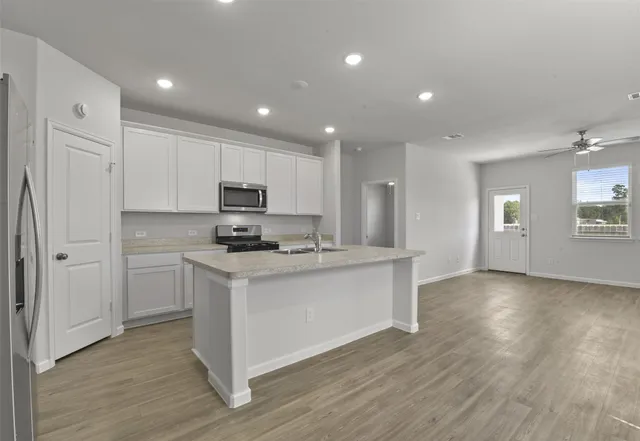 a kitchen with stainless steel appliances granite countertop a stove a sink and white cabinets