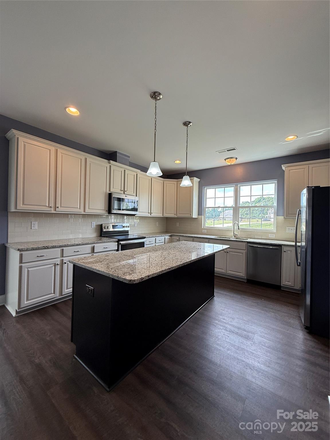 4048 Avis Way Monroe, NC 28110 - Photo 6 of 23 a kitchen with kitchen island granite countertop a sink cabinets and wooden floor