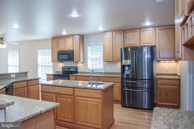 a kitchen with stainless steel appliances granite countertop a refrigerator sink and stove