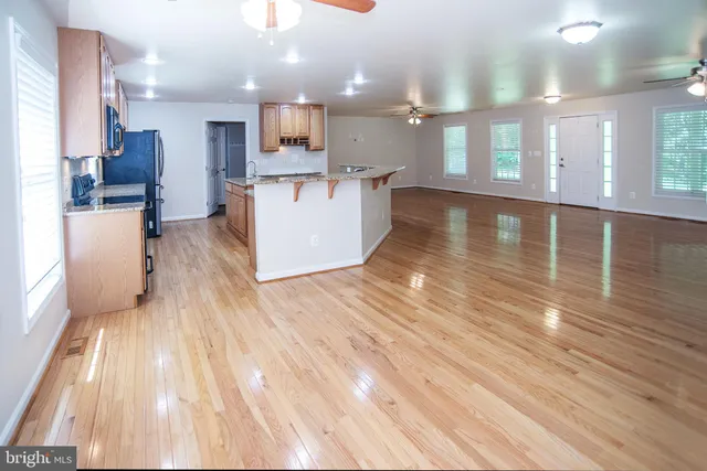 a view of a kitchen with kitchen island wooden floors stainless steel appliances